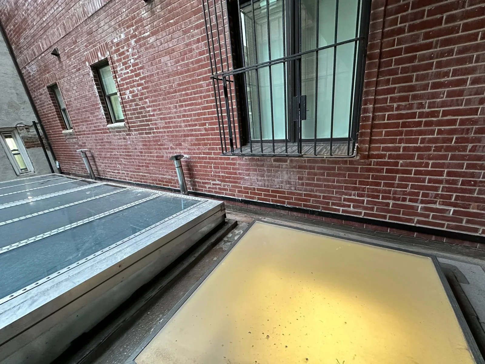 Yellow HVAC condensing unit installed on concrete pad against brick building wall