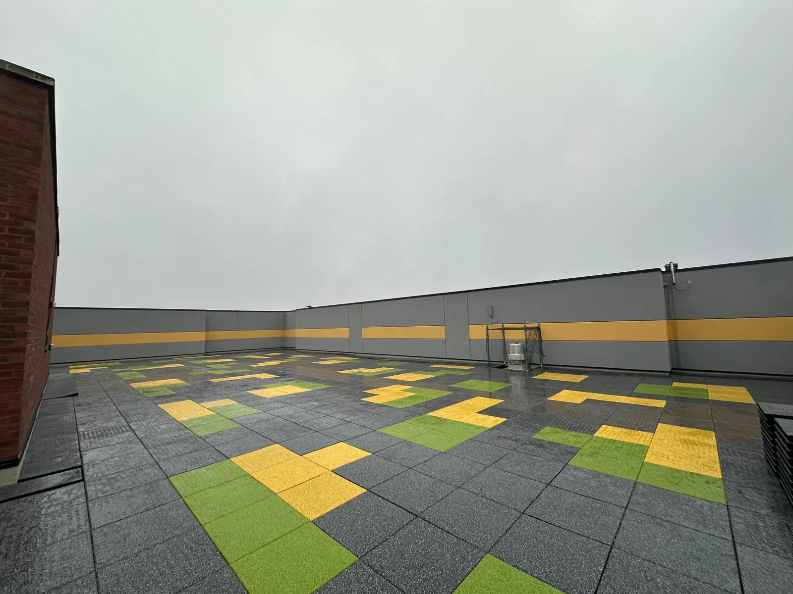 Rooftop HVAC installation with gray, yellow, and green modular tiles on commercial building