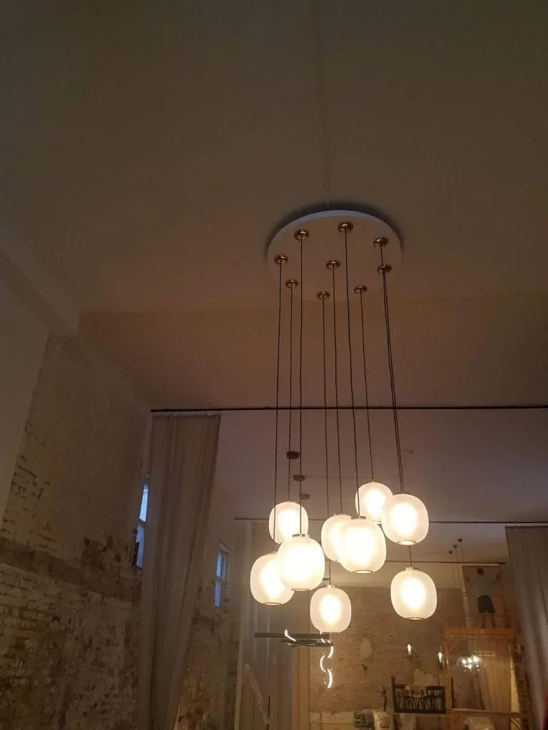 Nine frosted glass pendant lights suspended from bronze canopy in modern interior