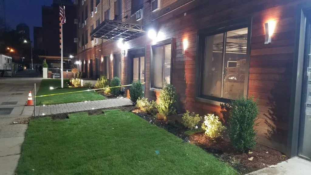 Illuminated brick commercial building with new landscaping, LED lighting, and manicured lawn at dusk