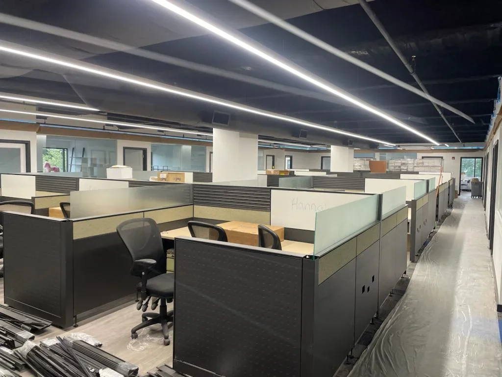 Commercial office with HVAC ductwork, linear LED ceiling lights, and workstation cubicles