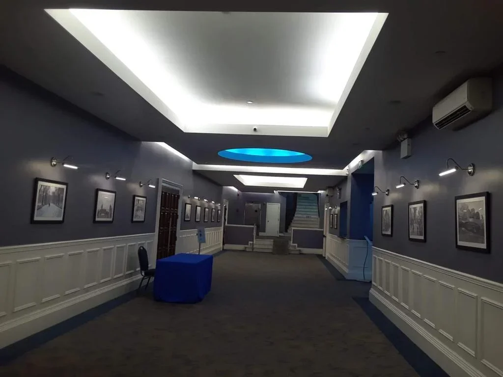 Commercial hallway with modern HVAC units, white wainscoting, and integrated ceiling climate control system