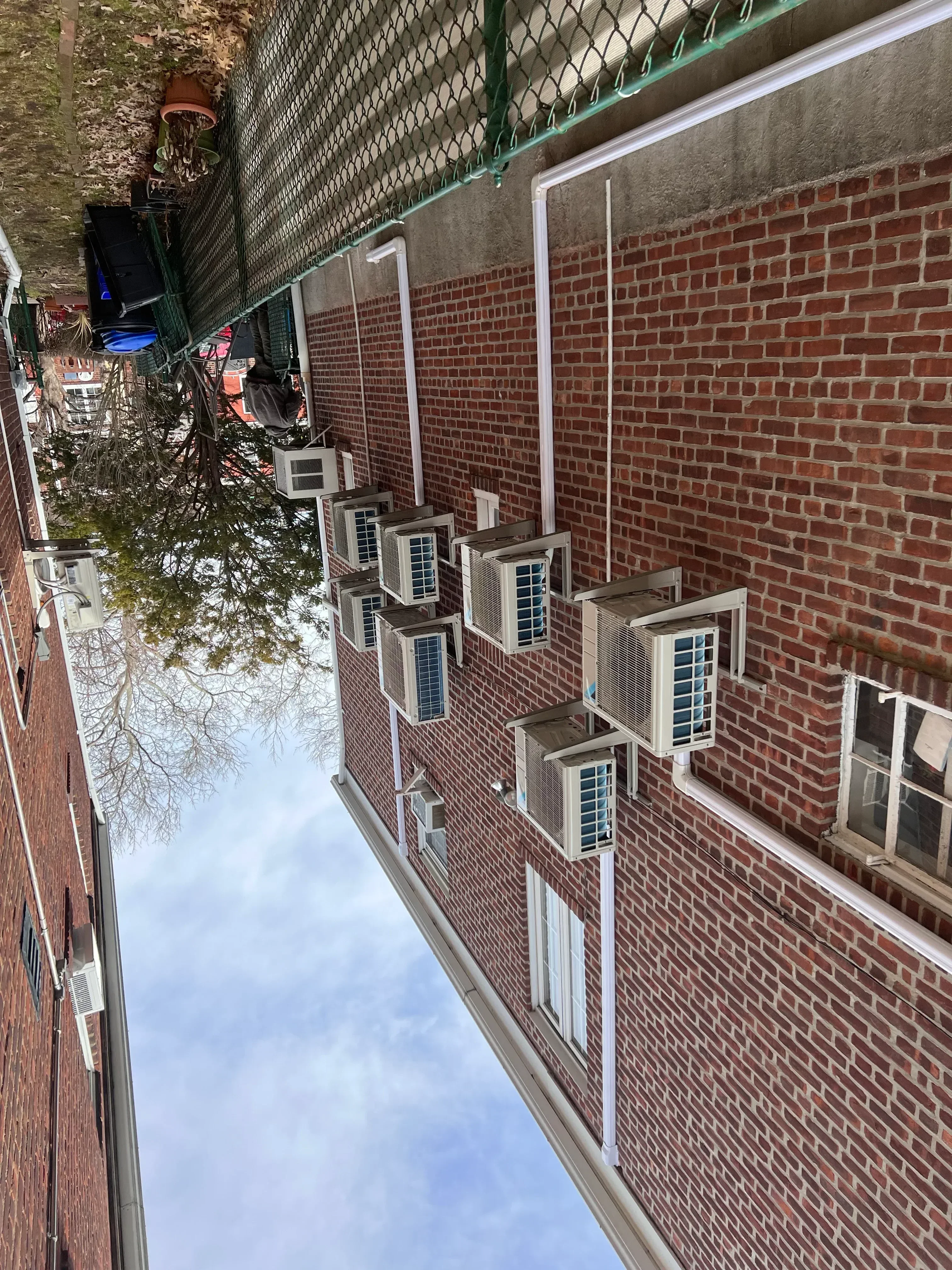 Brick residential building with multiple installed window AC units and white trim